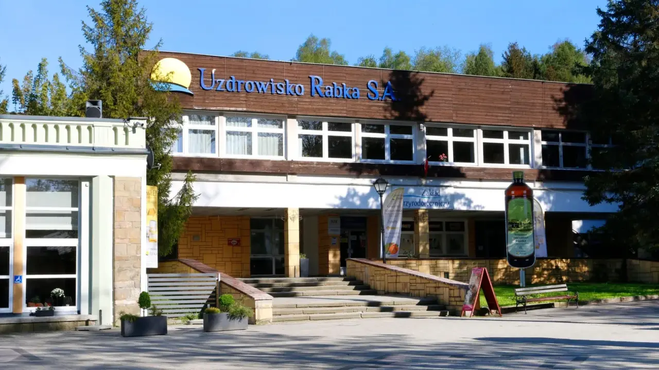 Sanatorium Jagiellonka w Rabce-Zdroju, budynek z napisem "Uzdrowisko Rabka S.A." i dużą butelką solanki.