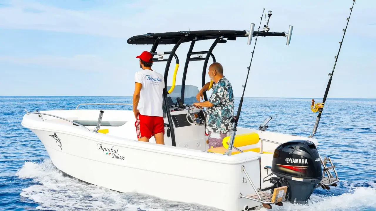 Deux hommes sur un bateau de pêche, avec un roll bar pour bateau, profitent de la mer bleue.