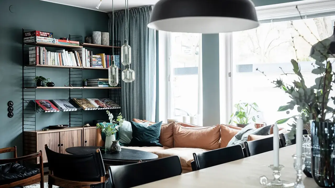 Vardagsrum med bokhylla i 50-talsstil, soffa i läder och stora fönster.