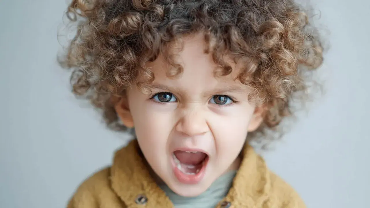 Niño de 1 año con rizos castaños, ojos marrones y expresión de enfado. Las rabietas son parte del desarrollo.
