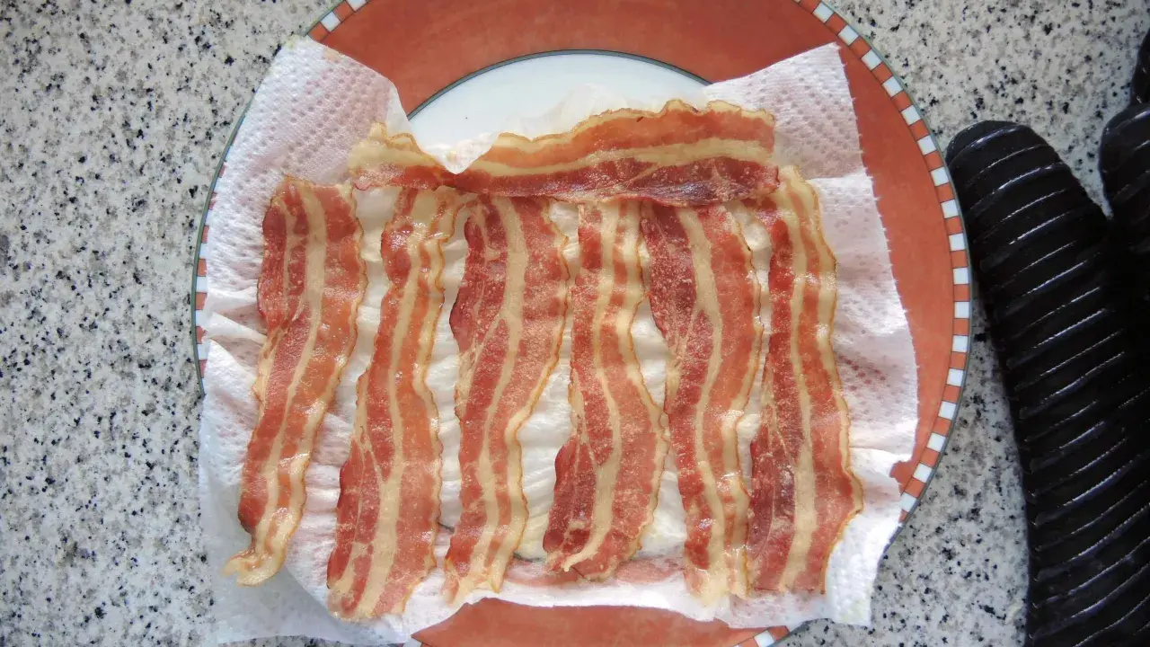 Fertig zubereitetes Bacon auf Küchenpapier auf einem Teller. Schnell und einfach in der Mikrowelle gemacht.