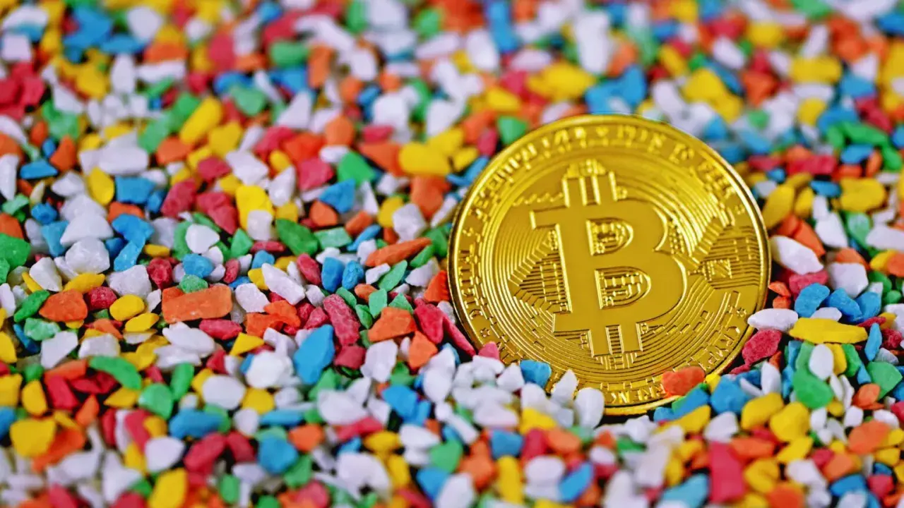 Złoty bitcoin wśród kolorowych kamyczków. Czy to symbol bogactwa, które James Howells stracił na zawsze?