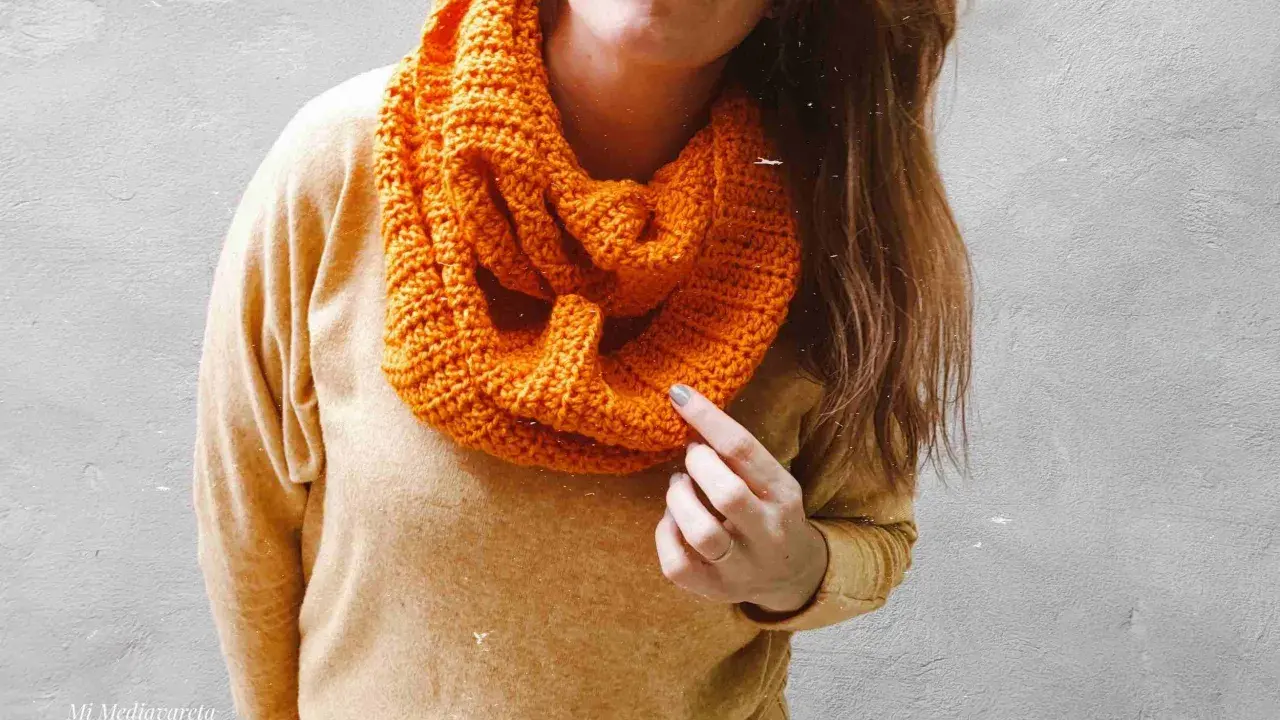 Persona con una bufanda naranja tejida, lista para el frío.
