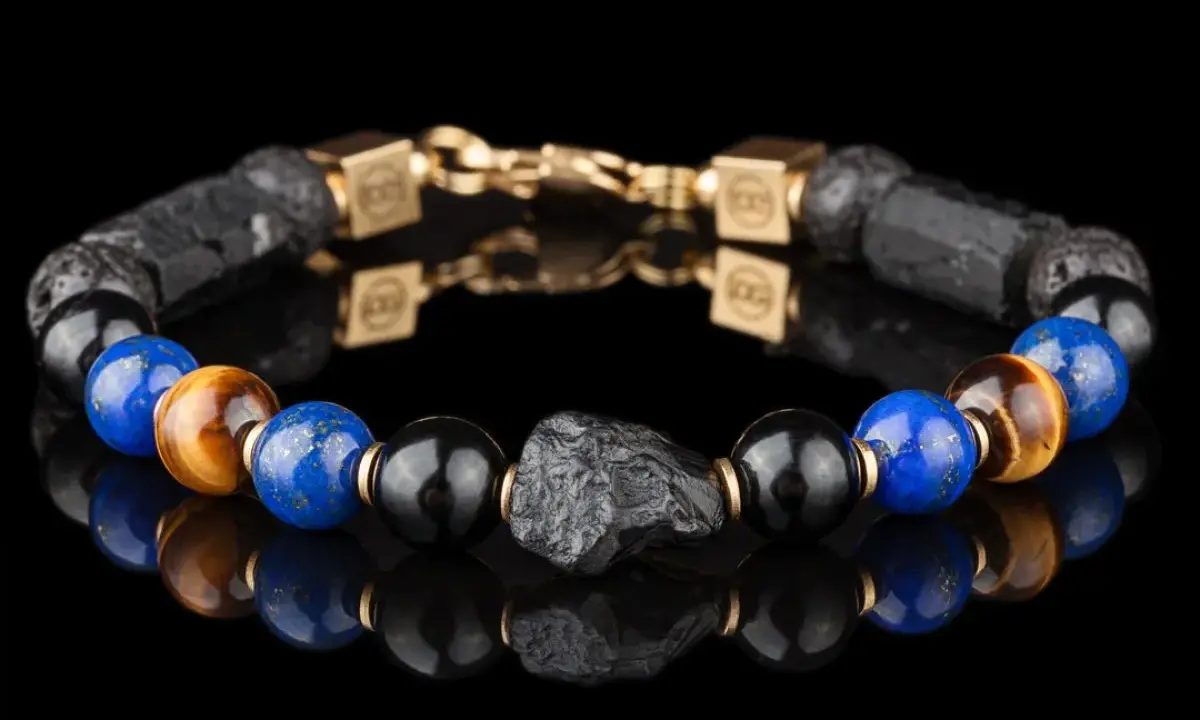 Bransoleta z lapis lazuli i kamienia wulkanicznego, ozdobiona złotymi elementami. Idealna dla osób szukających swojego znaku zodiaku.