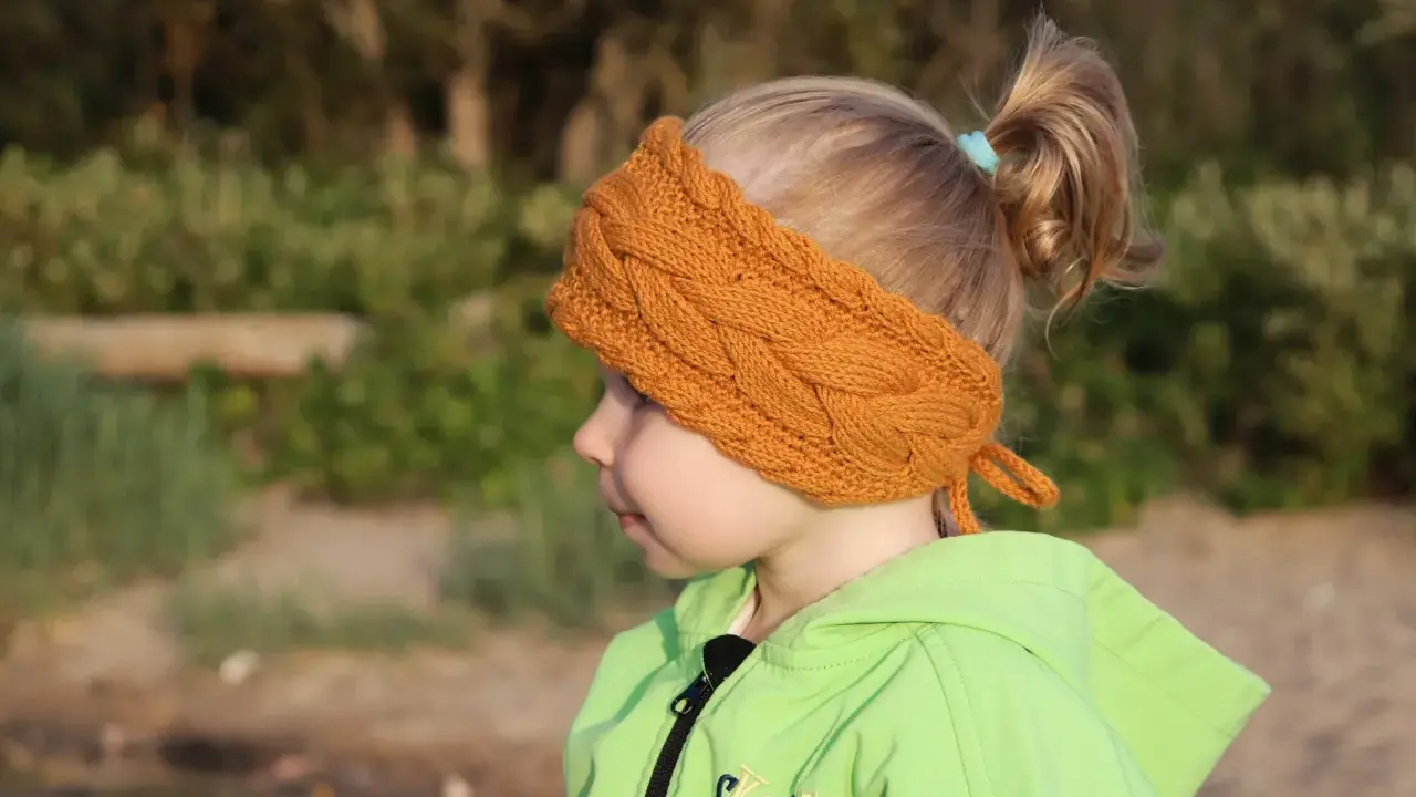 Niña con diadema de lana tejida, ideal para aprender como hacer diademas de lana para niñas.