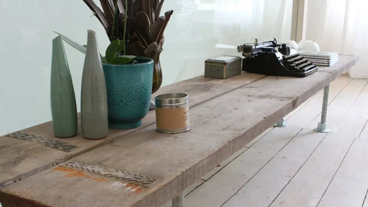 Une table basse rustique, idéale pour savoir que faire avec des vieilles planches de bois. Elle est décorée d'une machine à écrire, de vases et d'une bougie.