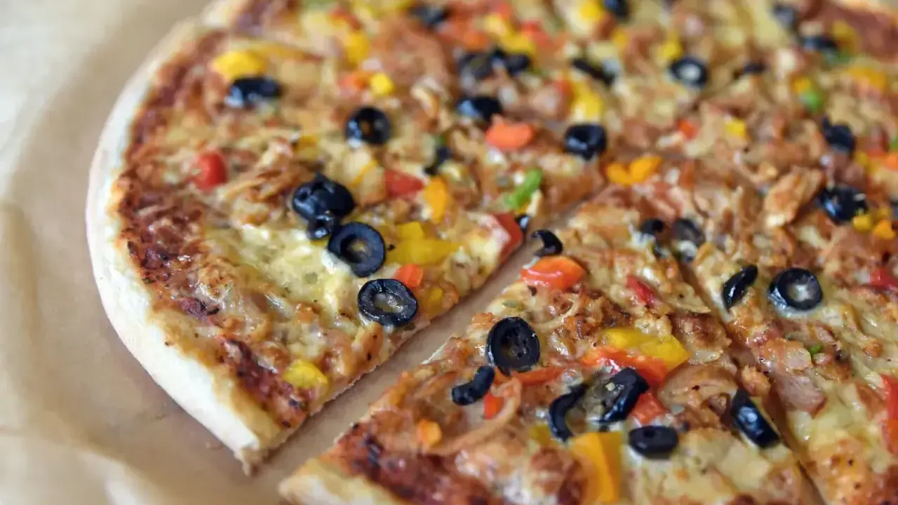 Pyszna pizza z oliwkami i kolorową papryką, jeden z wielu apetycznych rodzajów pizzy.