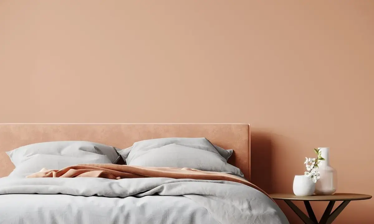 Lit de chambre douillet avec mur et tête de lit couleur pêche. Quelle couleur chambre pour une ambiance chaleureuse et apaisante.