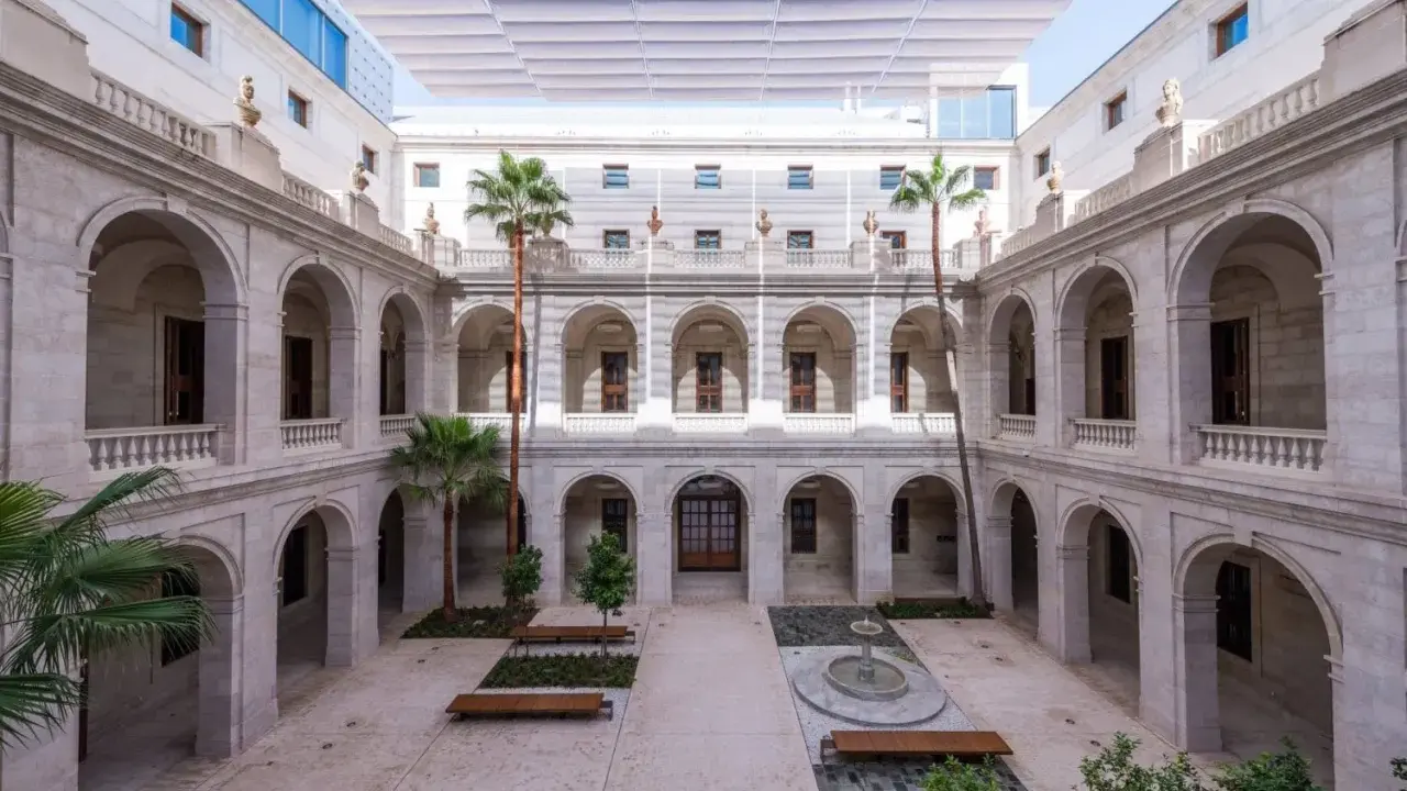 Hof des Malaga Museums mit Arkaden, Palmen und einem Brunnen.