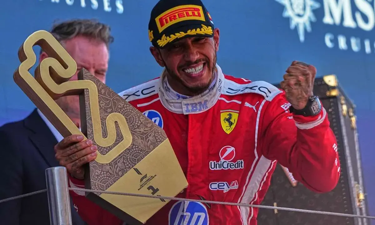 Hamilton im Ferrari-Outfit jubelt mit Pokal.
