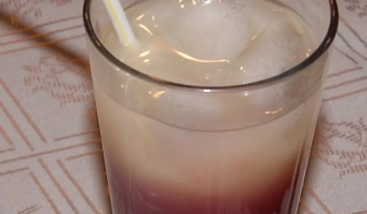 Szklanka z drinkiem z lodem i słomką, z widocznym podziałem na warstwy koloru.