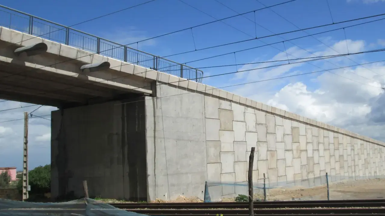 El estribo del puente de hormigón se alza imponente, sosteniendo la estructura sobre las vías del tren.