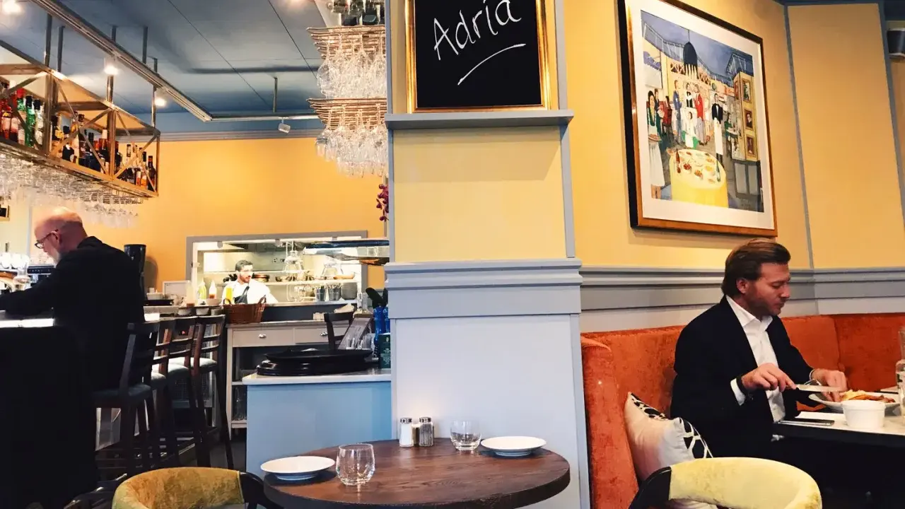 Man äter på Adria ristorante & bar. En tavla med texten "Adria" hänger på väggen.