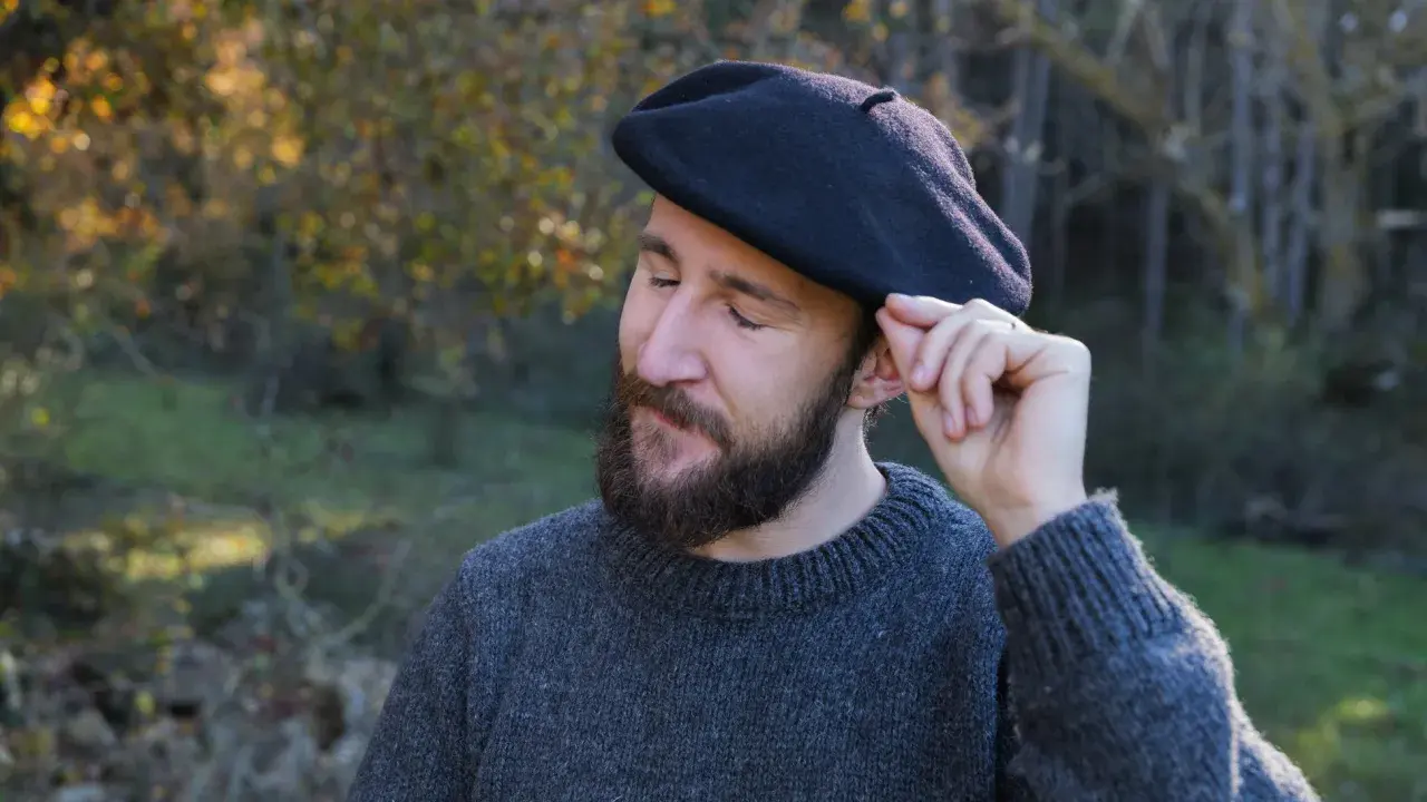 Hombre con barba ajustando su boina de lana, ideal para aprender como hacer una boina de lana.