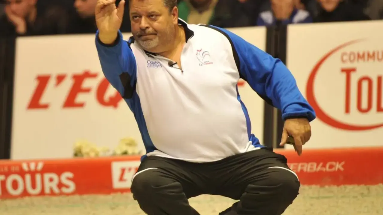 Un joueur de pétanque français connu, en pleine action, lance sa boule.