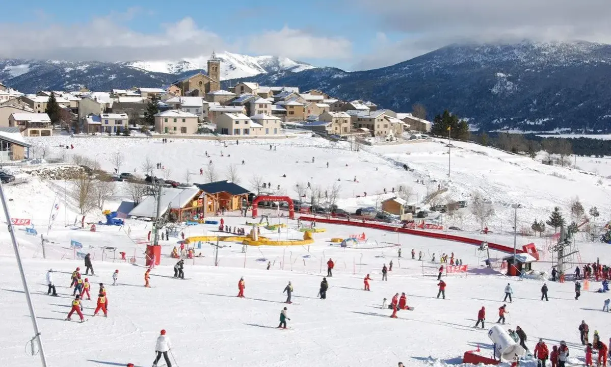Un pueblo nevado en el Pirineo francés con niños esquiando y divirtiéndose en la nieve.