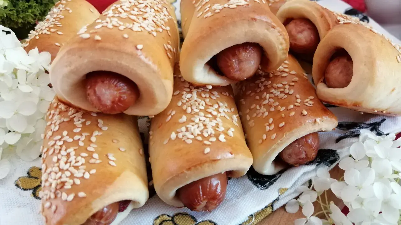 Złociste, pieczone mini hot dogi posypane sezamem, gotowe do podania. Idealne na przekąskę!
