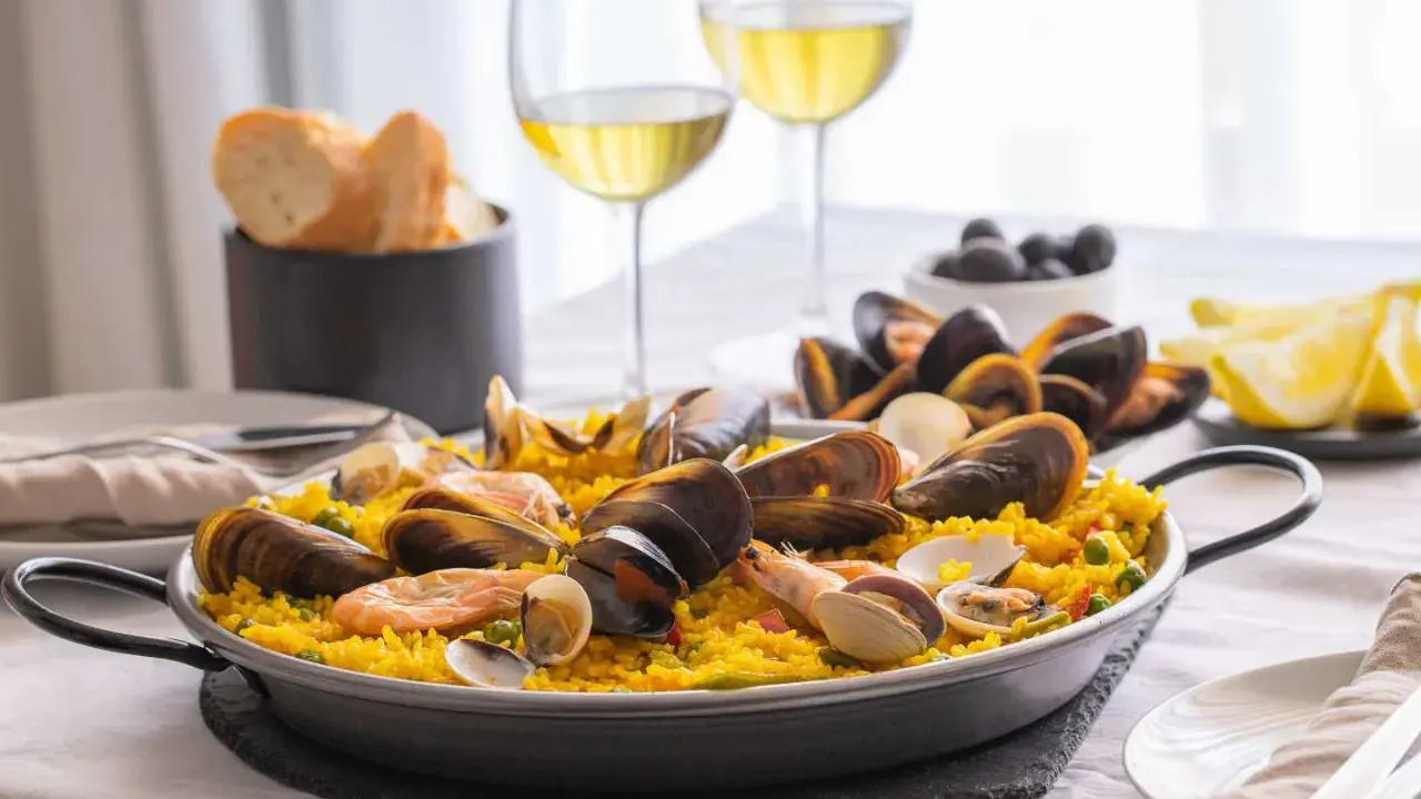 En härlig paella med skaldjur och ris, perfekt att avnjuta med ett glas vitt vin till paella. Serveras med citronklyftor och oliver.