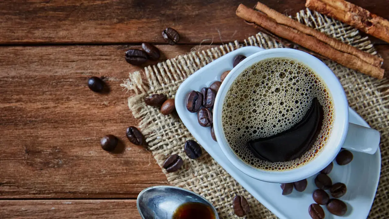 Heißer Kaffee mit Zimt, frisch zubereitet von einem Vollautomaten, duftet auf rustikalem Holz.