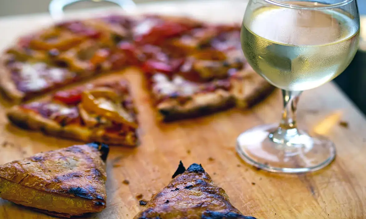 En saftig pizza med ett glas vitt vin till. Perfekt för en mysig kväll.