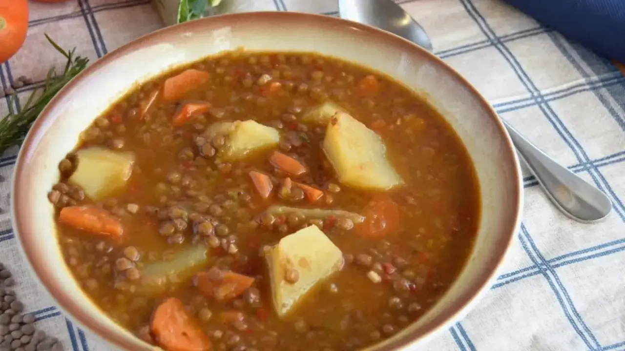 Un plato humeante de lentejas estofadas al estilo Arguiñano, con patatas y zanahorias, listo para disfrutar.