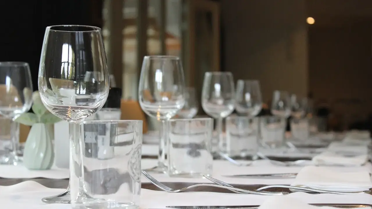 Un verre à eau et un verre à vin sont positionnés sur une table dressée, prêts pour un repas.