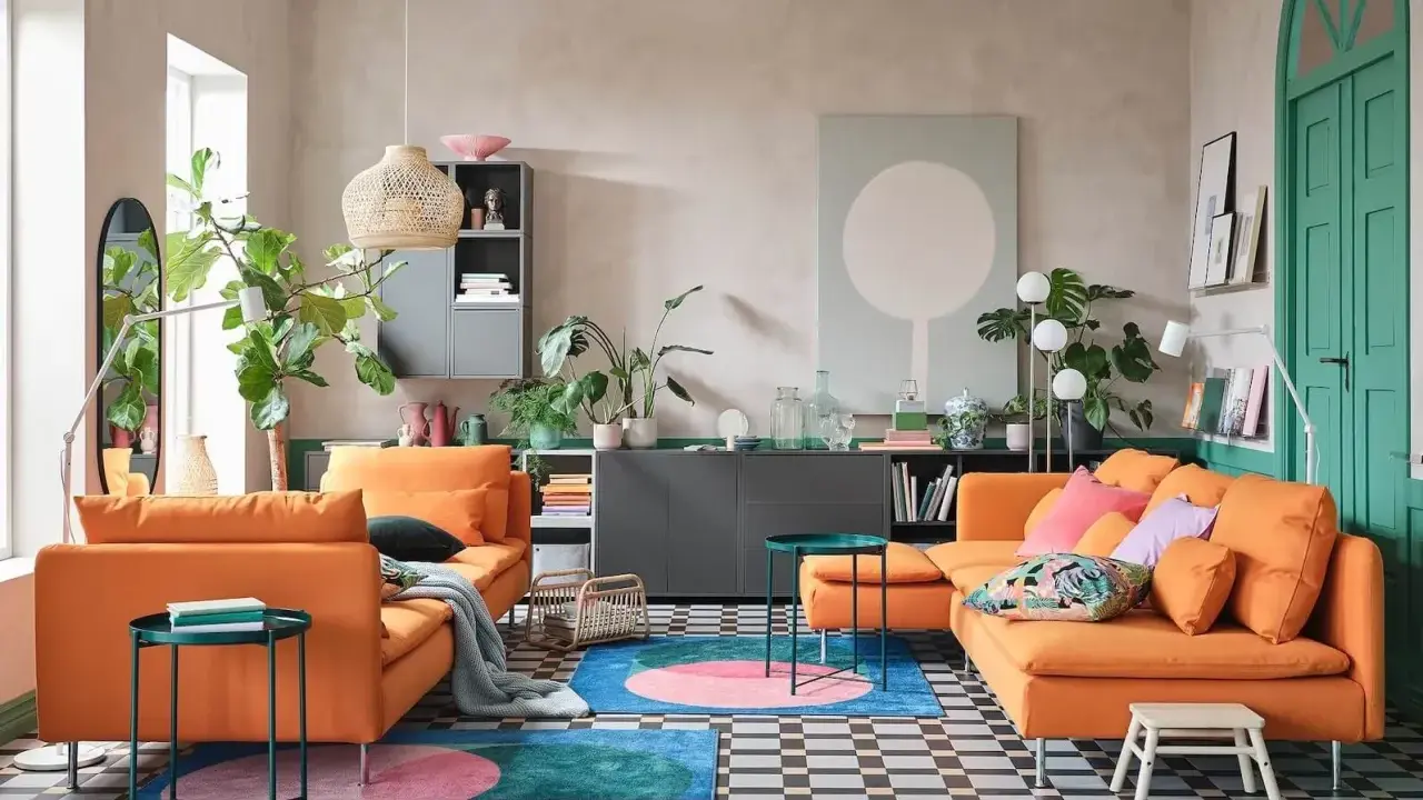 Un salon moderne avec deux canapés orange vif. Un tapis rond aux couleurs vives et des plantes vertes apportent de la vie. L'idée est d'associer 2 canapés différents pour un style unique.
