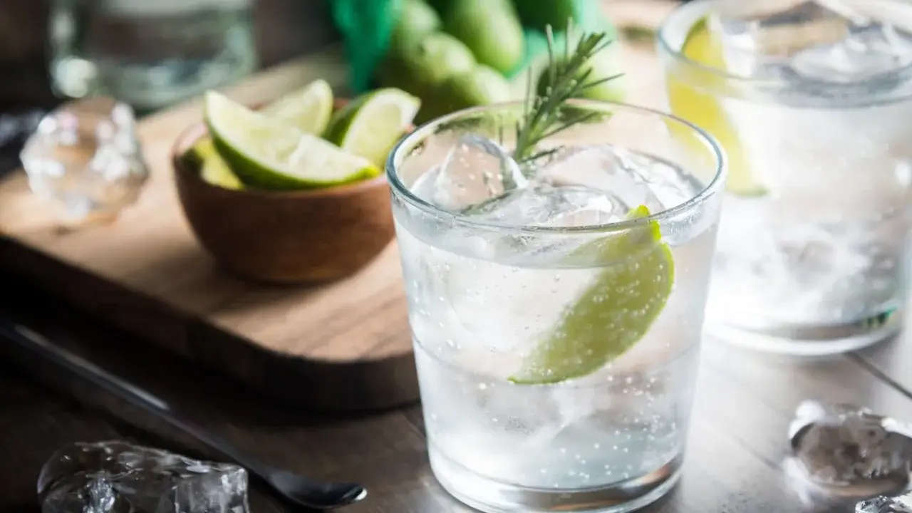 Kto pije gin z tonikiem? Orzeźwiający drink z lodem, limonką i rozmarynem, gotowy do degustacji.