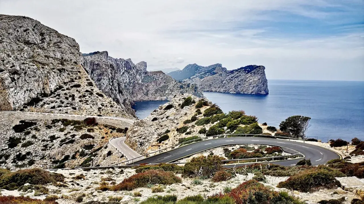 Carretera sinuosa en acantilados rocosos con vistas al mar azul. Un viaje en coche por un paisaje espectacular.