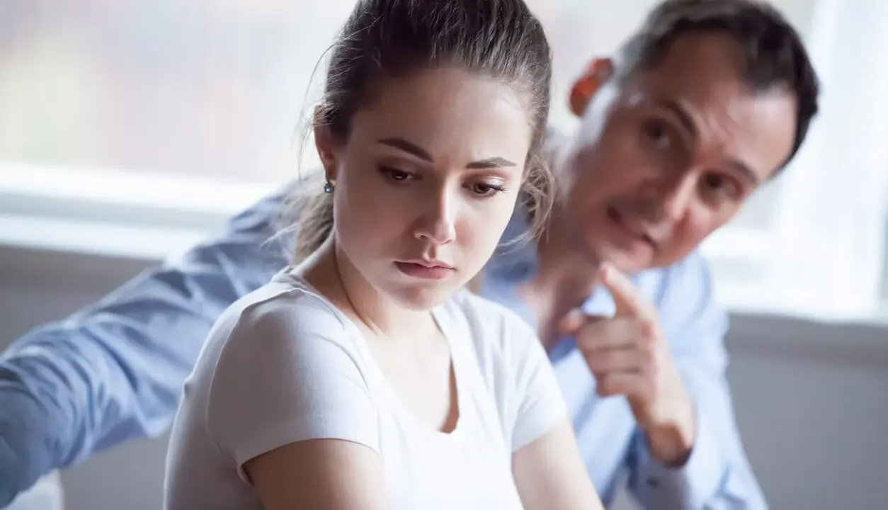 Mujer triste, hombre la señala. Una escena que evoca el trauma bonding español, donde el dolor crea un vínculo perverso.