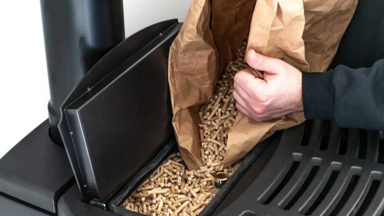 Persona rellena el depósito de una estufa de pellets con combustible.