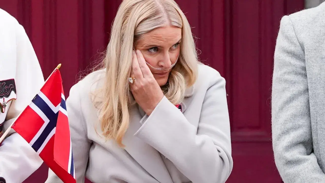 Kronprinsessan Mette-Marit med syrgasgrimma, en påminnelse om hennes sjukdom, håller en norsk flagga.