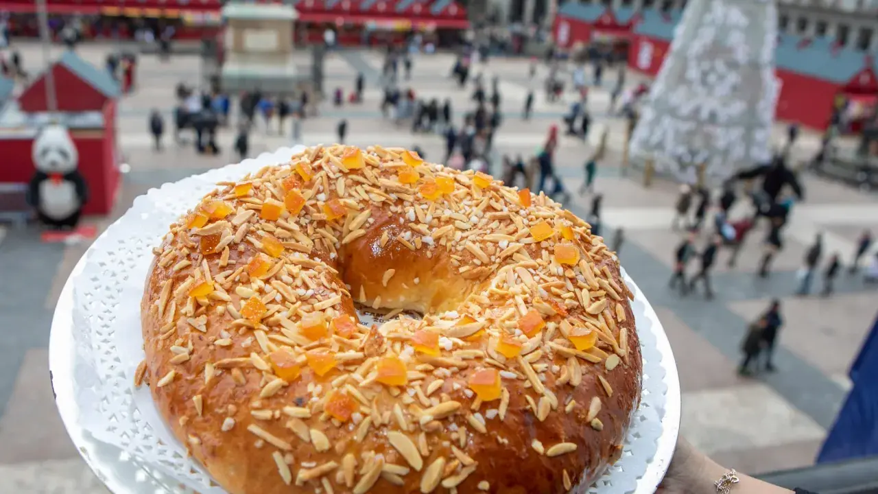 El mejor roscón de Madrid, adornado con almendras y fruta confitada, se presenta en la Plaza Mayor, un festín visual y delicioso.