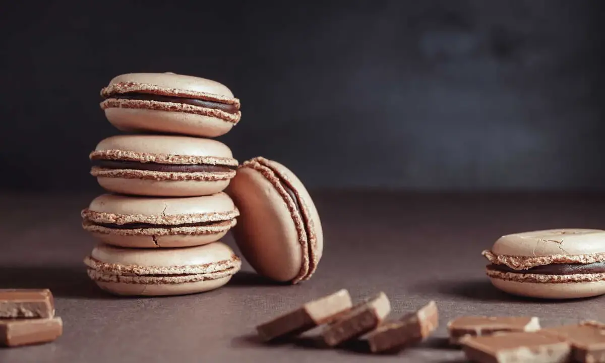 Une pile de macarons de Noël à la garniture chocolatée, avec des morceaux de chocolat sur le côté.