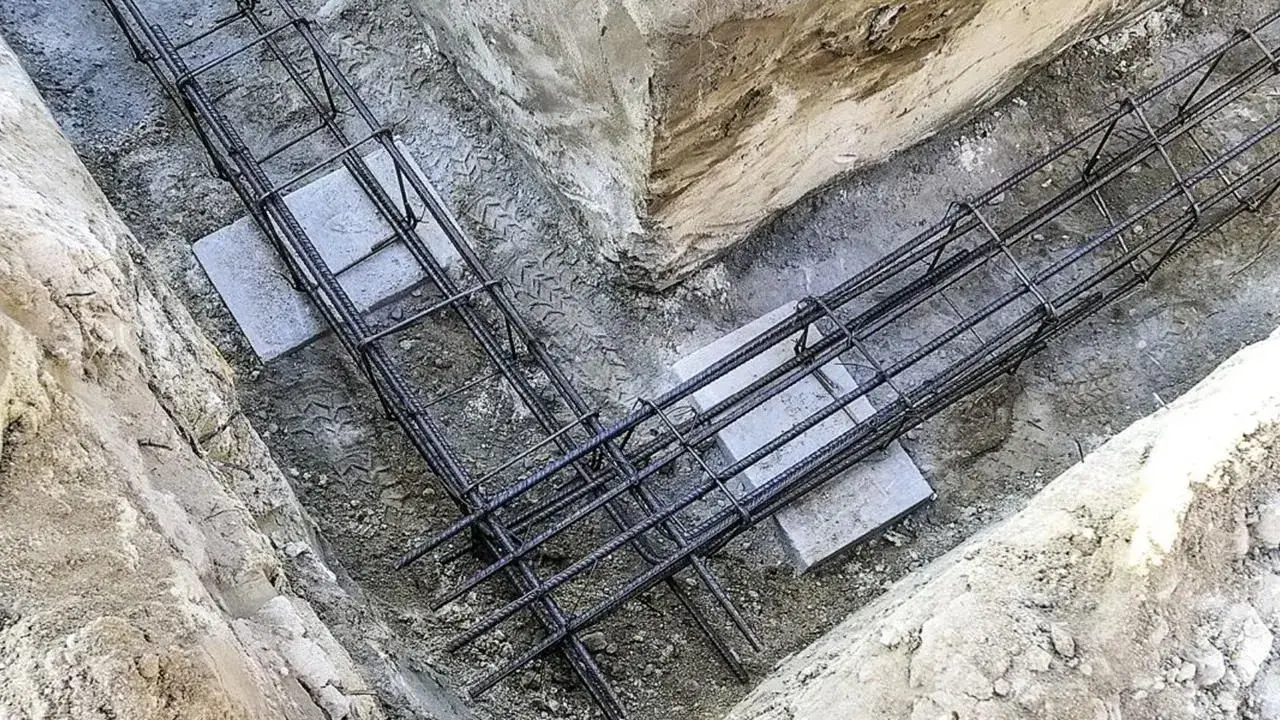 Gotowe zbrojenie ławy fundamentowej w wykopie. Stalowe pręty tworzą solidną konstrukcję, gotową na zalanie betonem.