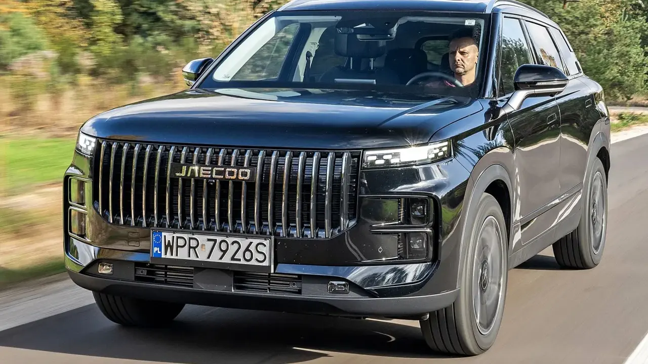 Czarny Jaecoo 7 w ruchu, z kierowcą za kierownicą. Sprawdź aktualną jaecoo 7 cena i dowiedz się więcej o tym SUV-ie.