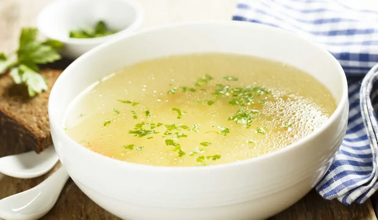 Aromaticzny rosół z perliczki, ozdobiony natką pietruszki, podany z kromką chleba. Idealny na chłodne dni.