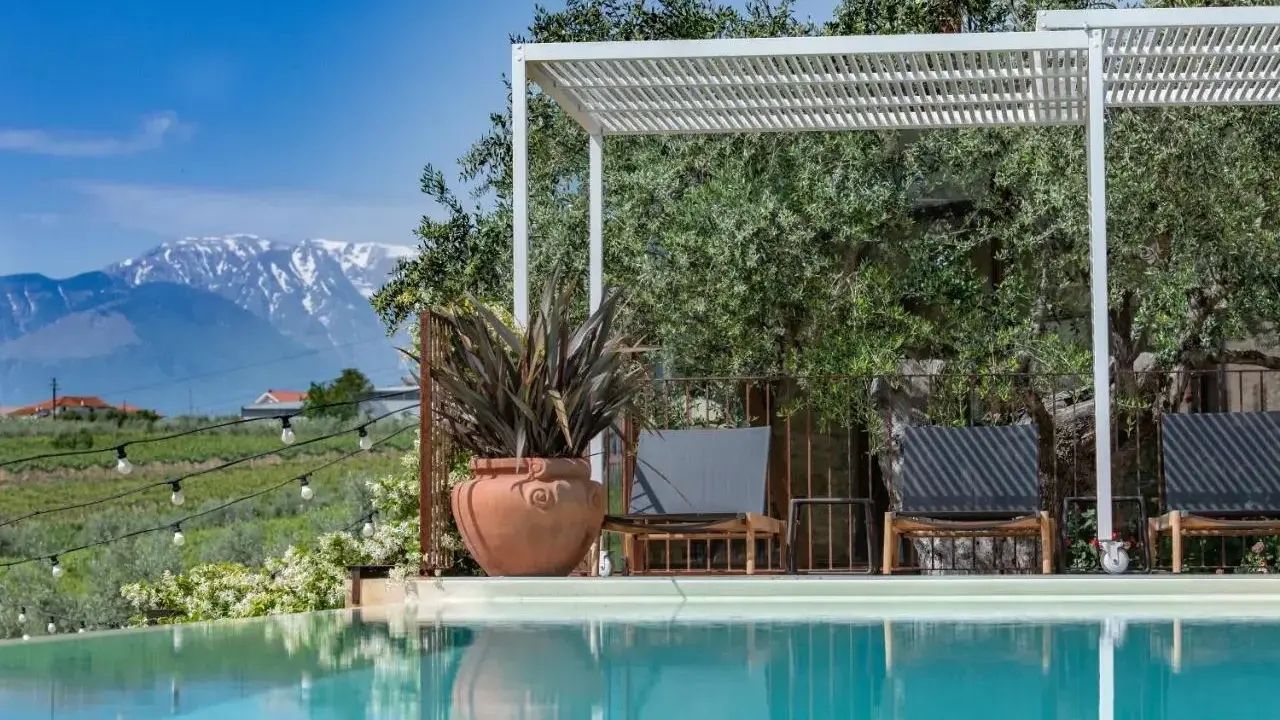 Piscina con vista sulle montagne innevate, ideale per una vacanza in Abruzzo montagna. Relax sotto il pergolato tra ulivi secolari.