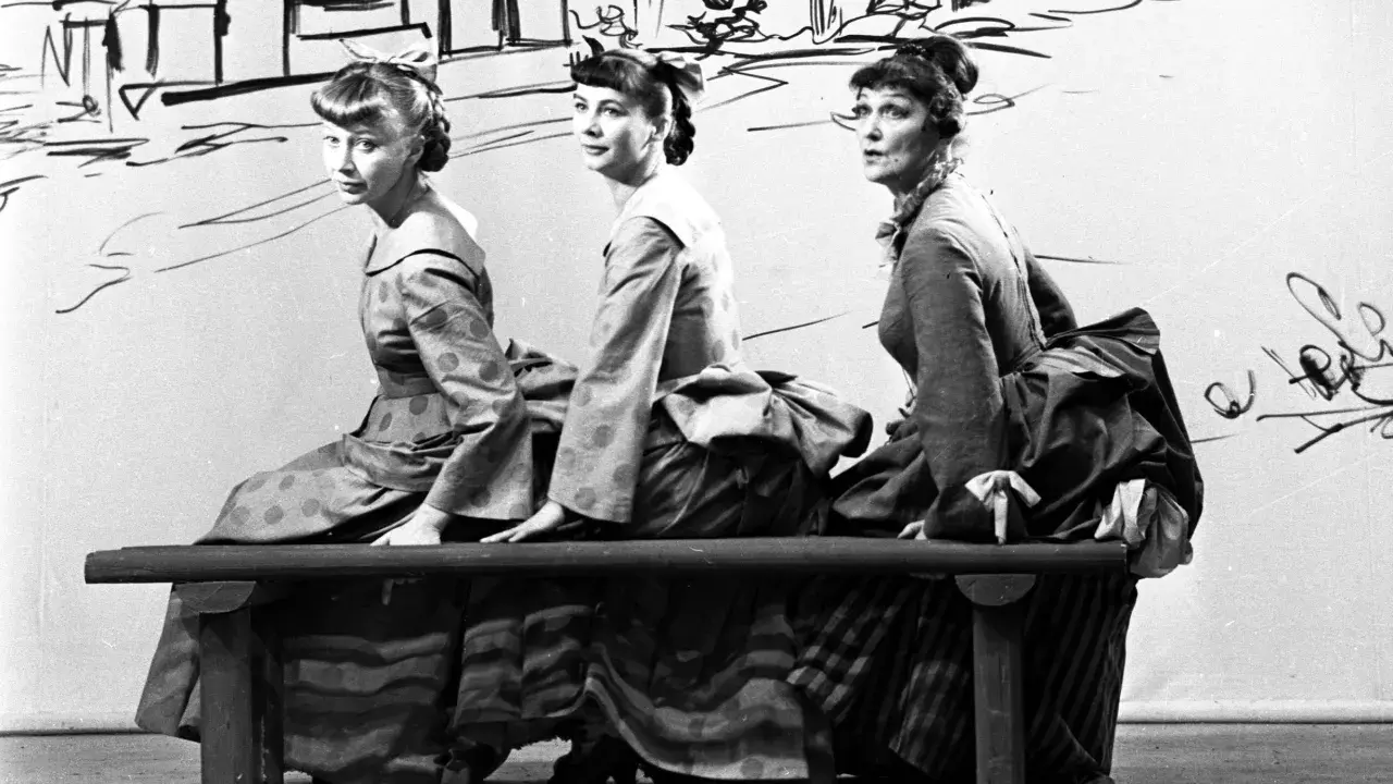Trzy kobiety w historycznych strojach siedzą na ławce. Czy jedna z nich to guwernantka, która pilnuje porządku?