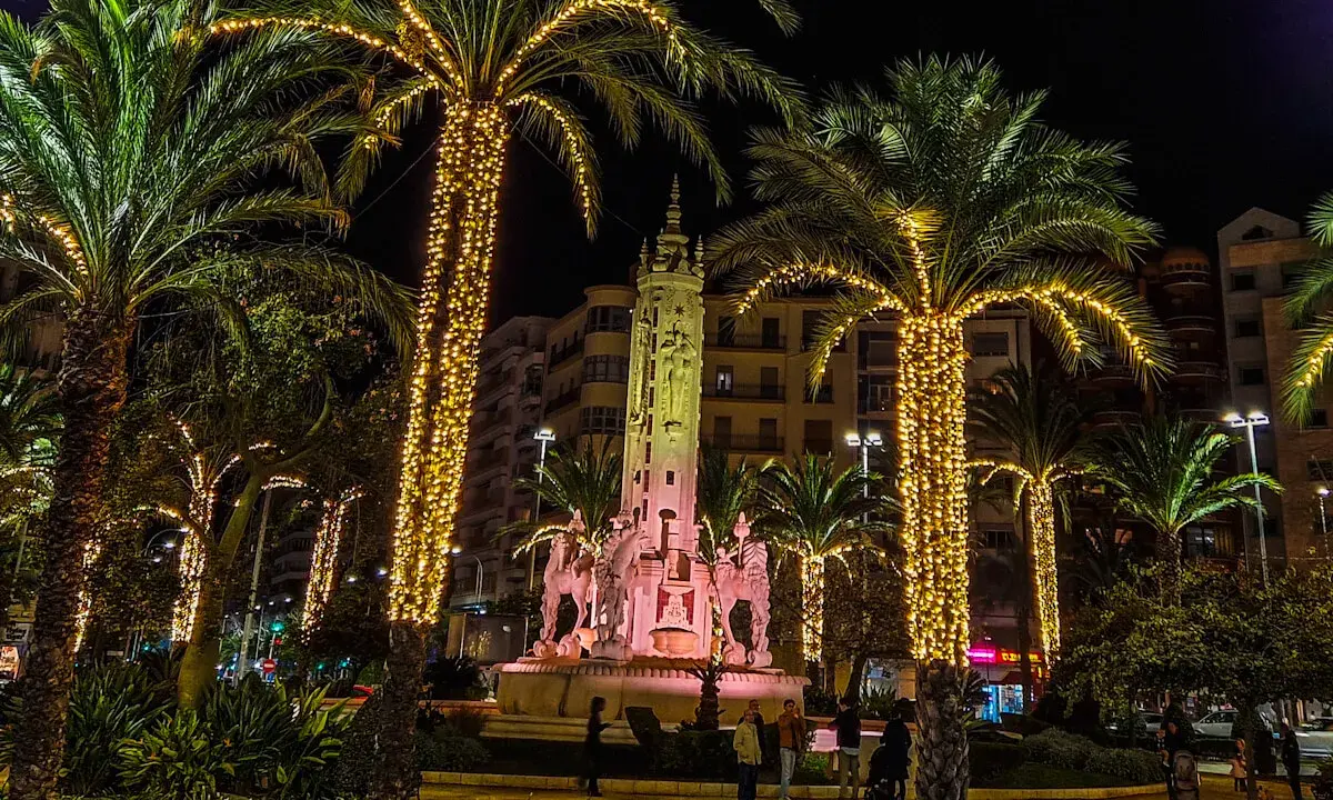 Nocna iluminacja palm i fontanny z rzeźbami. Wspaniała atmosfera, jakby trwały święta w Hiszpanii.