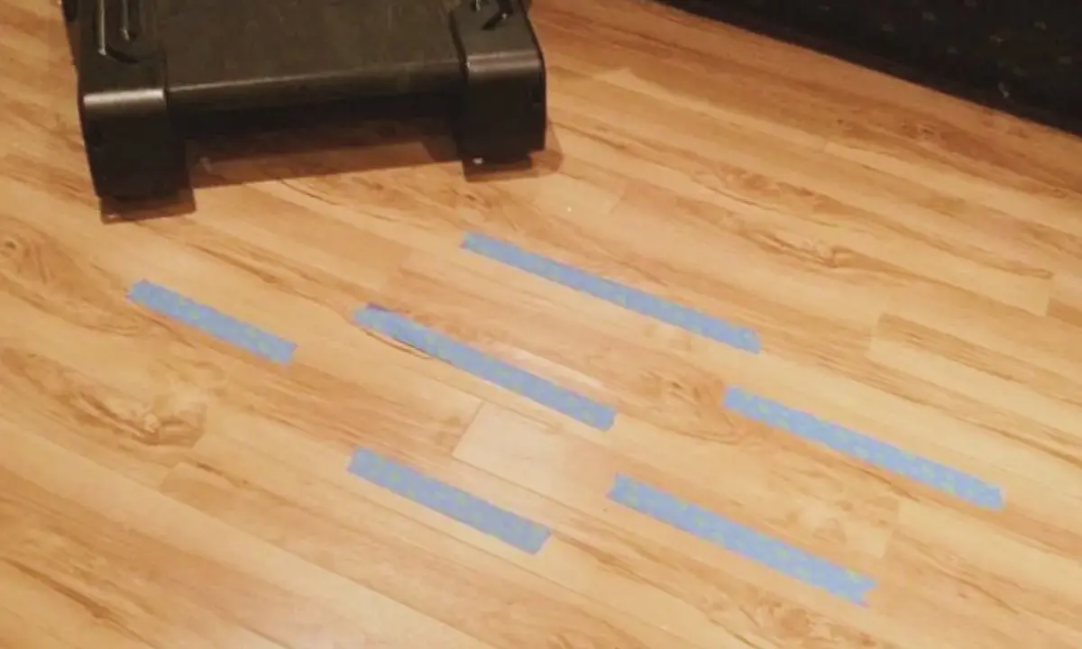 Marcando con cinta azul las áreas del suelo laminado que necesitan reparar.