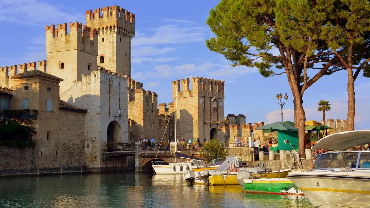 Castello Scaligero sul lago, ideale per vacanze in Lombardia. Barche ormeggiate in un porto pittoresco.