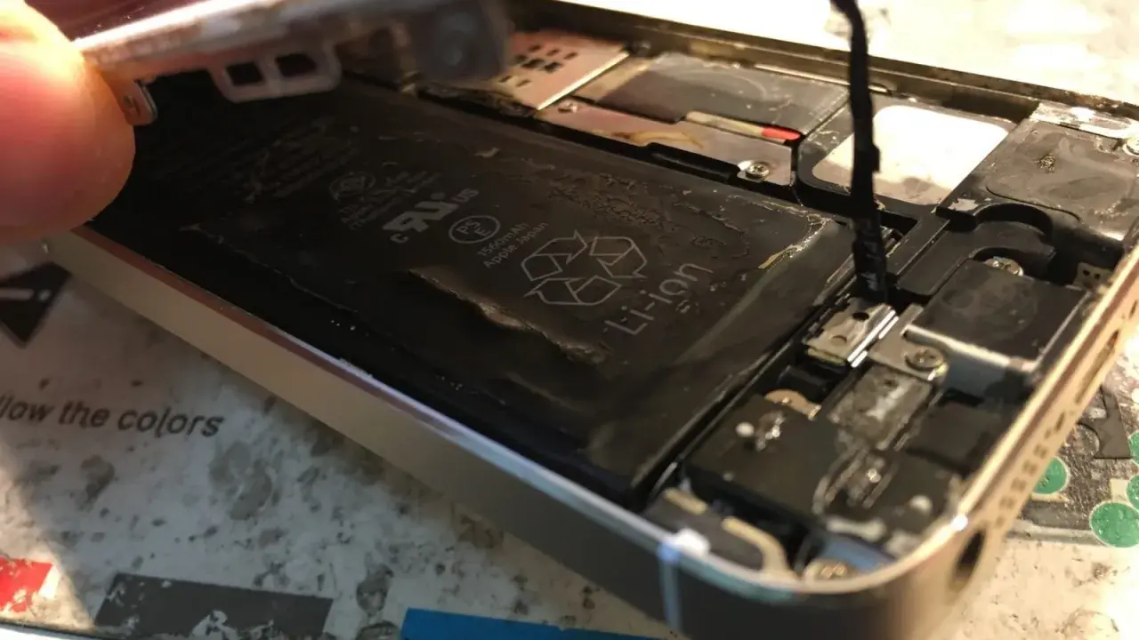 Naprawa iPhone po zalaniu. Widoczna otwarta obudowa, bateria Li-ion i elementy wewnętrzne.