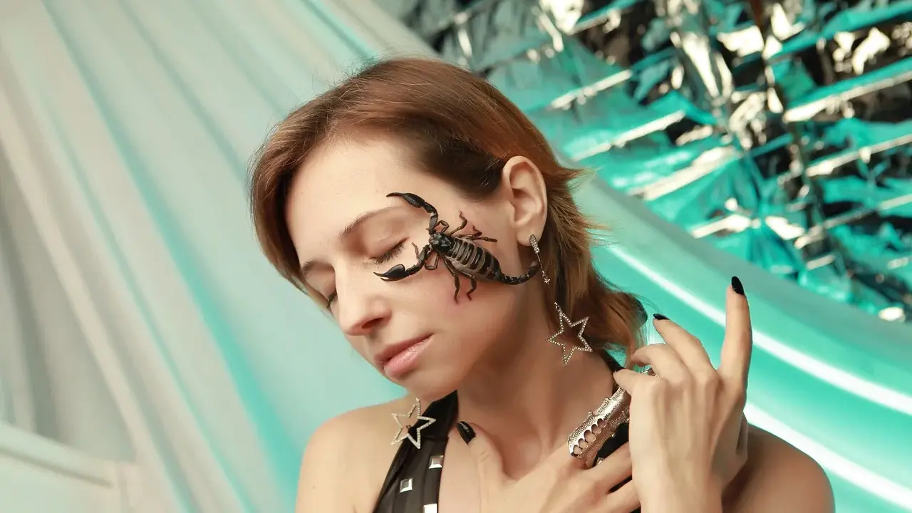 Scorpione sul viso di una donna, un esempio estremo di desensibilizzazione sistematica. Gioielli a forma di stella e un anello elaborato completano il look.