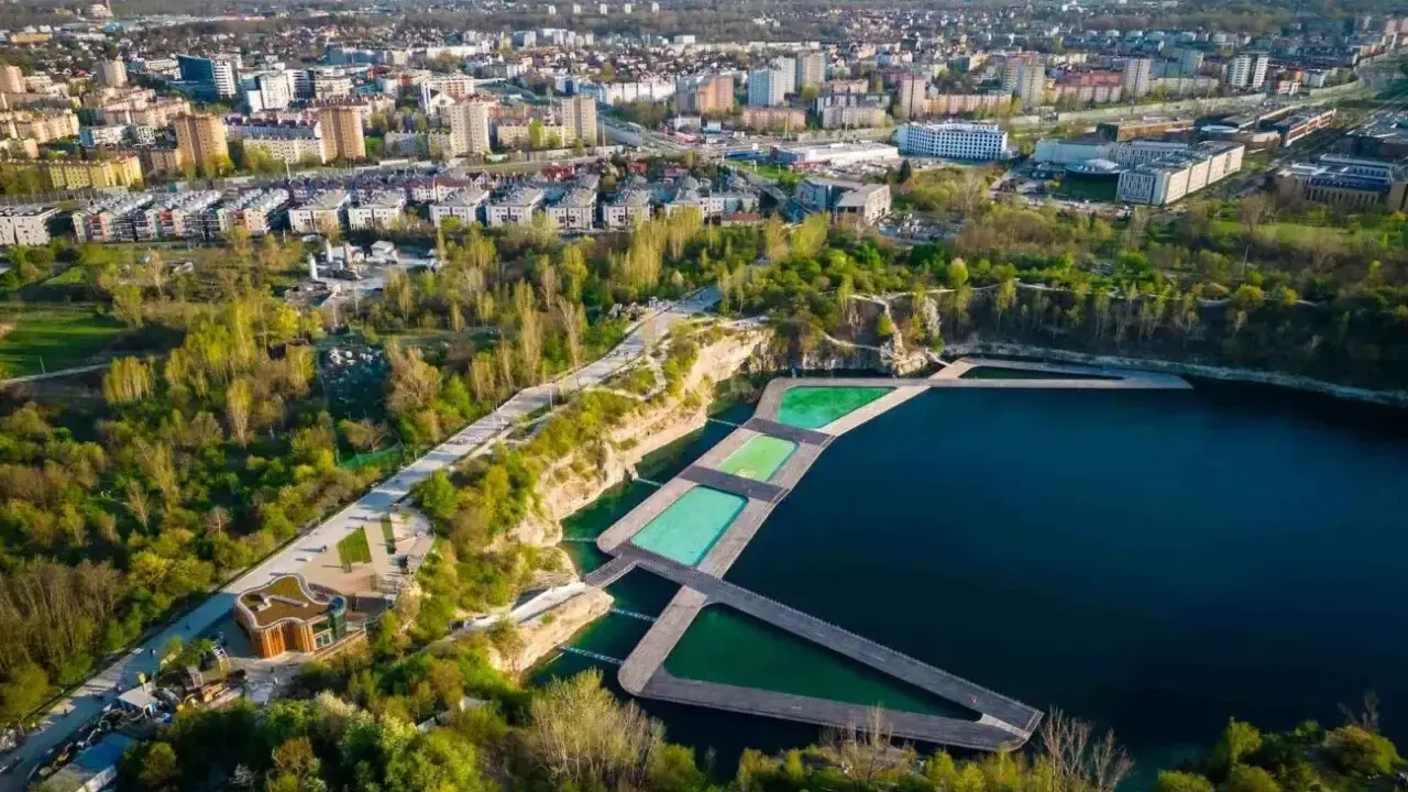 Widok na zakrzówek kapielisko z basenami w kamieniołomie, otoczone zielenią i zabudową miejską.