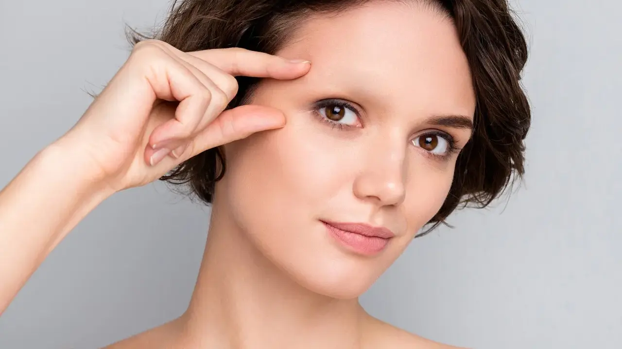 Une femme examine son visage, préoccupée par une possible alopécie sourcil.