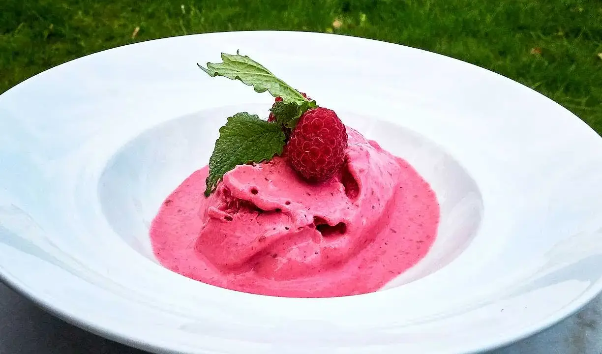 Hallonglass i en vit skål, toppad med hallon och mynta. Perfekt för ett enkelt hallonglass recept.