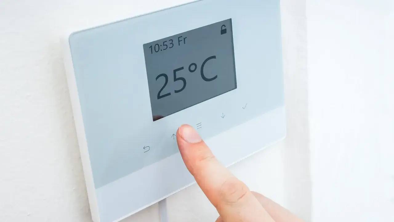 Dedo ajustando uno de los tipos de termostatos para calefacción, mostrando 25°C.