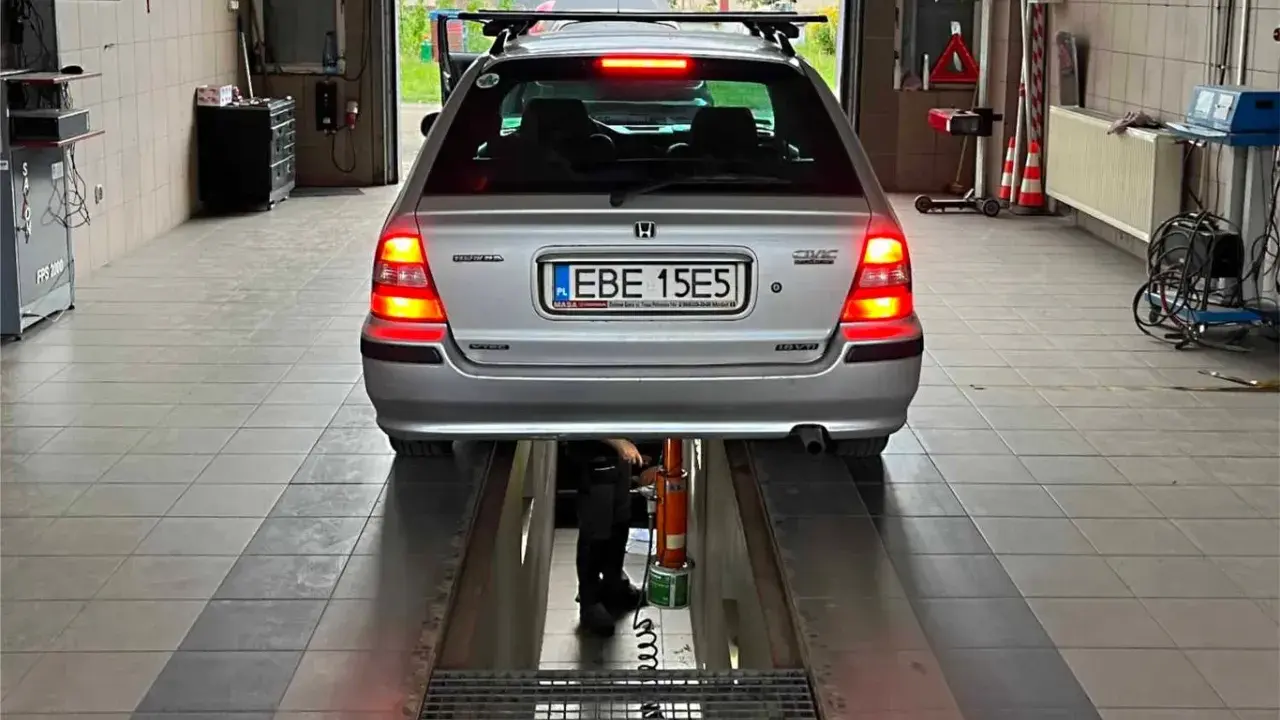 Srebrny kombi Honda Civic na podnośniku w warsztacie. Zastanawiasz się, ile kosztuje przerejestrowanie samochodu?