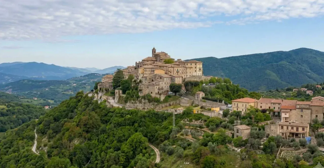 Borgo medievale su una collina verde, uno dei tanti **paesi da vedere vicino Roma**, con case in pietra e un campanile.